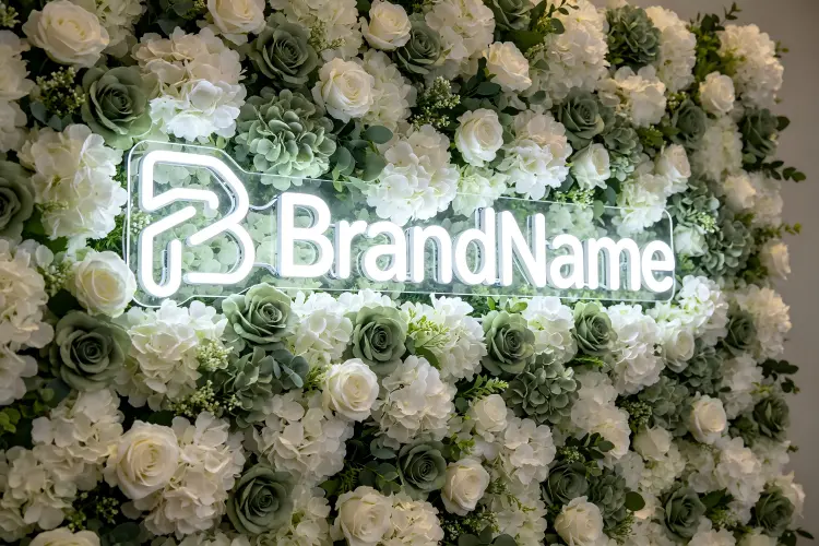 Artificial flower wall backdrop at corporate gala event with branded neon sign