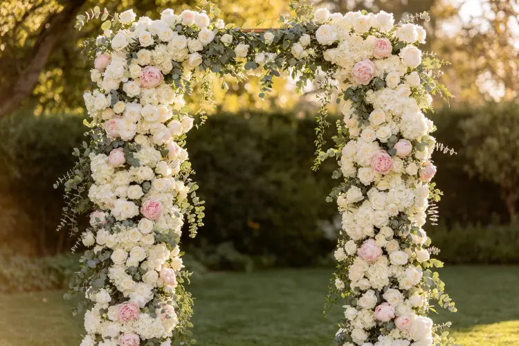 Tall floral columns framing a wedding ceremony aisle with white and blush roses
