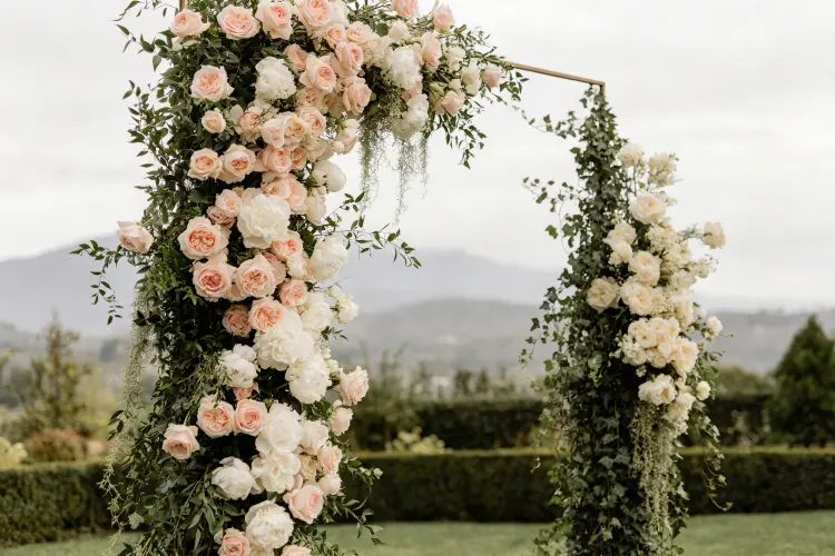 Floral columns paired with a broken arch asymmetrical design at outdoor wedding