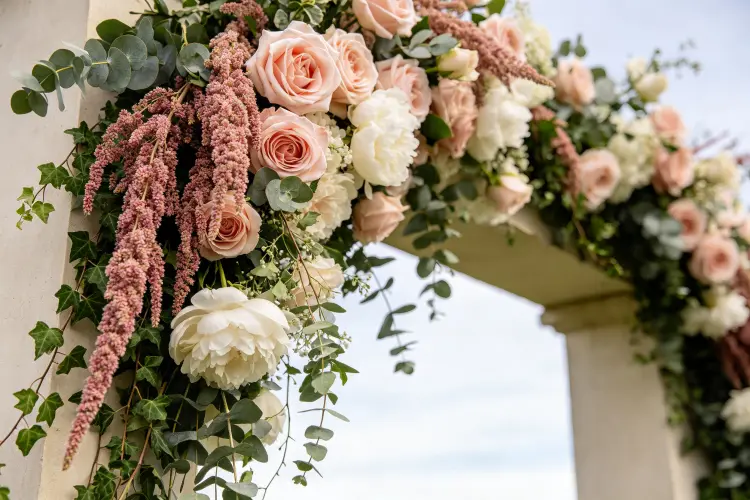 Close-up of asymmetrical broken arch design with trailing greenery and blush roses